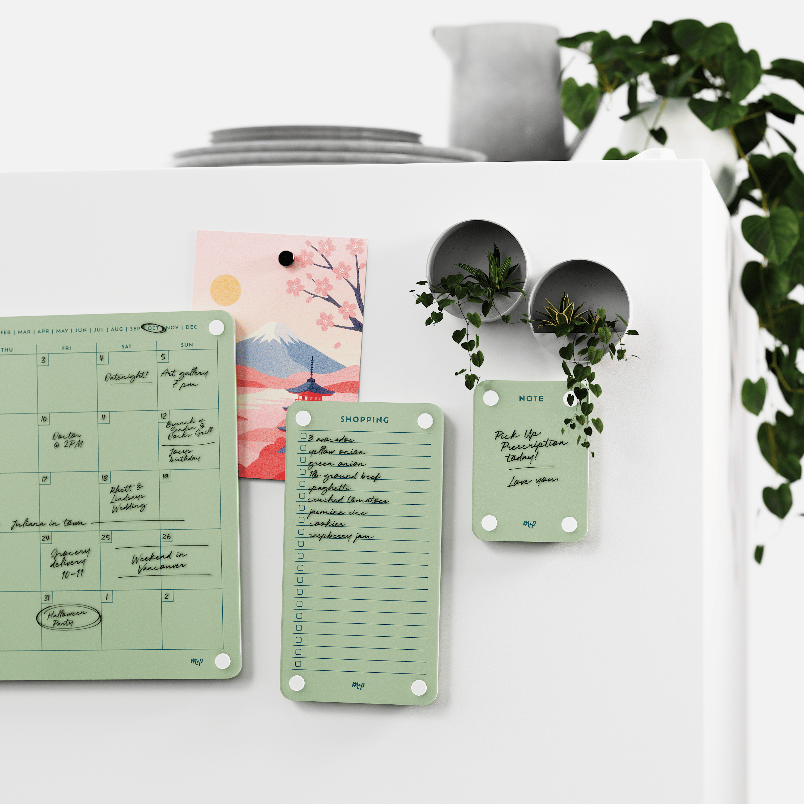 Matcha green calendar, shopping list and note board on a white wall beside two magnetic planters